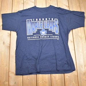 May include: A navy blue t-shirt with a white graphic of the Toronto Maple Leafs logo and the text "Toronto Maple Leafs National Hockey League".