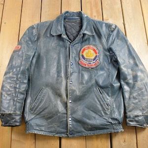 May include: A blue leather jacket with a snap closure and a patch on the left chest that reads "Midland Barrie Maintenance".
