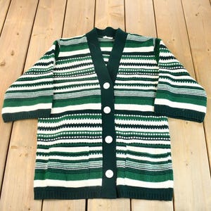 May include: A green and white striped cardigan with a button-up front. The cardigan has a V-neck and is made of a soft knit fabric.