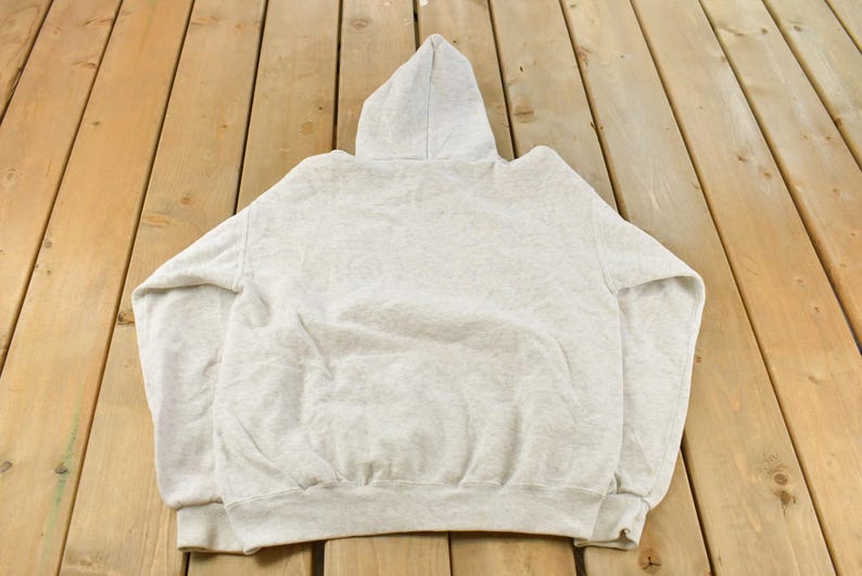Op de afbeelding: Een lichtgrijze gem&ecirc;leerde hoodie met lange mouwen, een capuchon met trekkoord en een kangoeroezak aan de voorzijde. Het kledingstuk is gemaakt van zachte fleecestof met geribbelde boorden aan de polsen en een geribbelde zoom aan de onderkant.