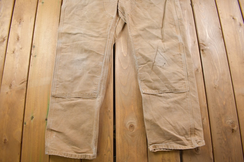 Puede incluir: Un par de pantalones de trabajo de color marr&oacute;n claro con parches reforzados en las rodillas. Los pantalones est&aacute;n hechos de una tela resistente y duradera y tienen un corte holgado.