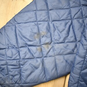 May include: A blue quilted jacket with a slight stain on the sleeve.