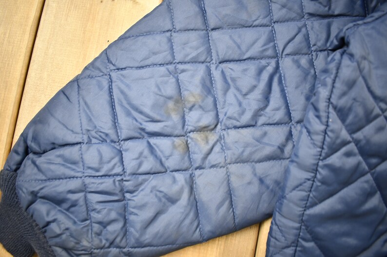 May include: A blue quilted jacket with a slight stain on the sleeve.