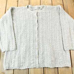 May include: A light gray cable knit cardigan sweater with a button front closure.
