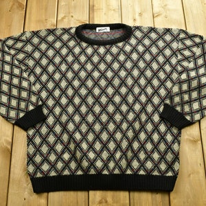 May include: A black, white, and red diamond patterned sweater with a black crew neck.