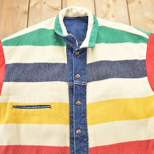 May include: A striped denim jacket with red quilted sleeves. The jacket has a white, green, blue, yellow, and red striped pattern. The jacket has a button closure and a pocket on the left side.