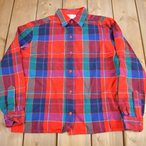 May include: A long-sleeved button-up shirt with a red, blue, green and purple plaid pattern.