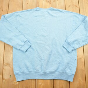 May include: A light blue sweatshirt with long sleeves and a crew neck.
