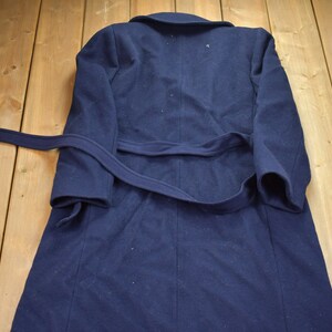 Pu&ograve; includere: Un cappotto di lana blu navy con cintura da annodare. Il cappotto ha un design classico ed &egrave; perfetto per il clima freddo.