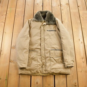 May include: A tan, long-sleeved jacket with a faux fur collar. The jacket has two large pockets on the front and a zipper closure.