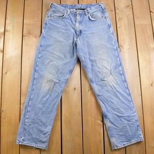 May include: A pair of light blue denim jeans with a faded look. The jeans have a classic five-pocket style and a straight leg.