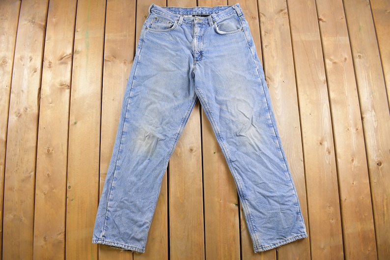 May include: A pair of light blue denim jeans with a faded look. The jeans have a classic five-pocket style and a straight leg.