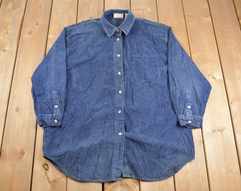 Peut inclure: Une chemise à manches longues rayée bleue avec un col boutonné et une poche poitrine.