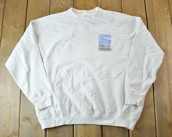 Puede incluir: Sudadera blanca de manga larga con un pequeño estampado gráfico de un paisaje con la palabra "Wisconsin" debajo.