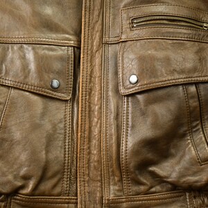 May include: A brown leather jacket with two large flap pockets and a zippered pocket on the chest.