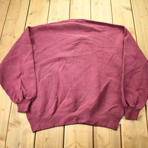May include: A maroon sweatshirt with long sleeves and a crew neck.