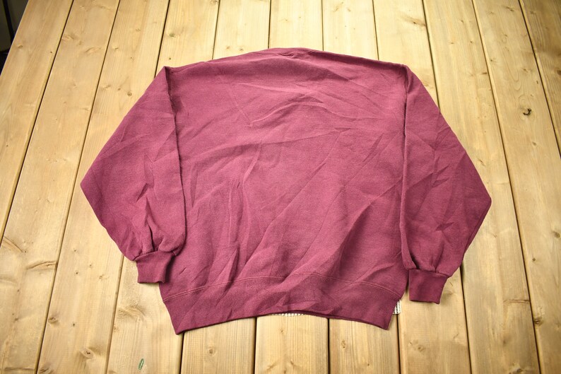 May include: A maroon sweatshirt with long sleeves and a crew neck.