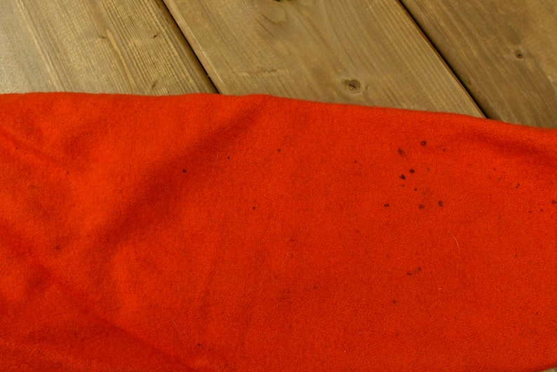 K&ouml;nnte beinhalten: Nahaufnahme eines leuchtend orangenen Stoffes mit ein paar kleinen dunkelbraunen Flecken.