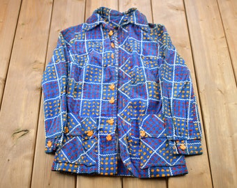 May include: A blue and white patterned shirt with orange buttons. The shirt has a collar and long sleeves.