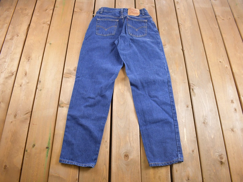 May include: A pair of blue denim jeans with a brown leather patch on the back.