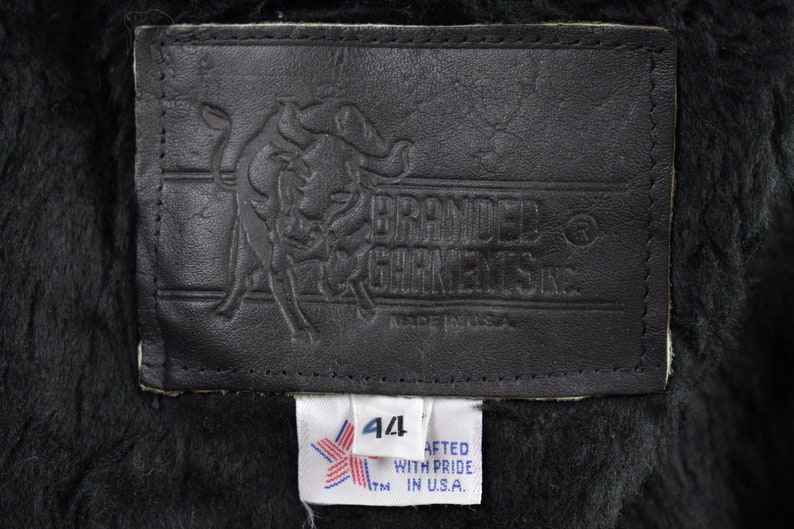 May include: A black leather label with a bull logo and the text "Branded Garments Inc."  A white label with a star and the text "44" and "Crafted with pride in U.S.A."
