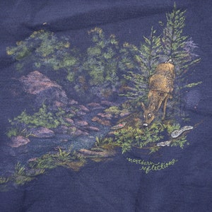 Puede incluir: Una sudadera azul marino con una escena de naturaleza impresa en la parte delantera. La escena presenta un ciervo bebiendo de un arroyo en un entorno de bosque. El texto "northern reflections" est&aacute; impreso debajo de la escena.