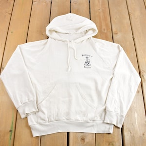 Puede incluir: Una sudadera con capucha blanca con el logotipo de la Universidad de Toronto impreso en la parte delantera.