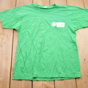 May include: A green t-shirt with a white clover and the word "Wrex" printed on the front.