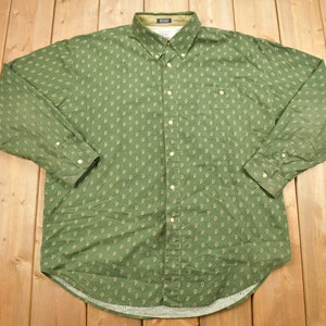 May include: A green long-sleeved button-down shirt with a white pattern of repeated letters.