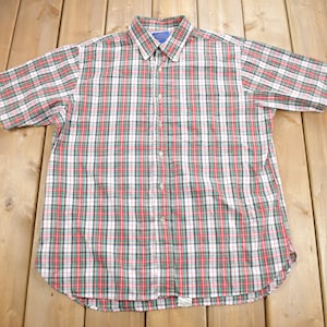 May include: A short-sleeved button-down shirt with a red, green and white plaid pattern.