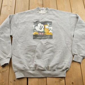 May include: A grey sweatshirt featuring a graphic of Mickey Mouse and Pluto embracing. The graphic is enclosed in a white border with the text "Together a friend with a fur" printed beneath it.