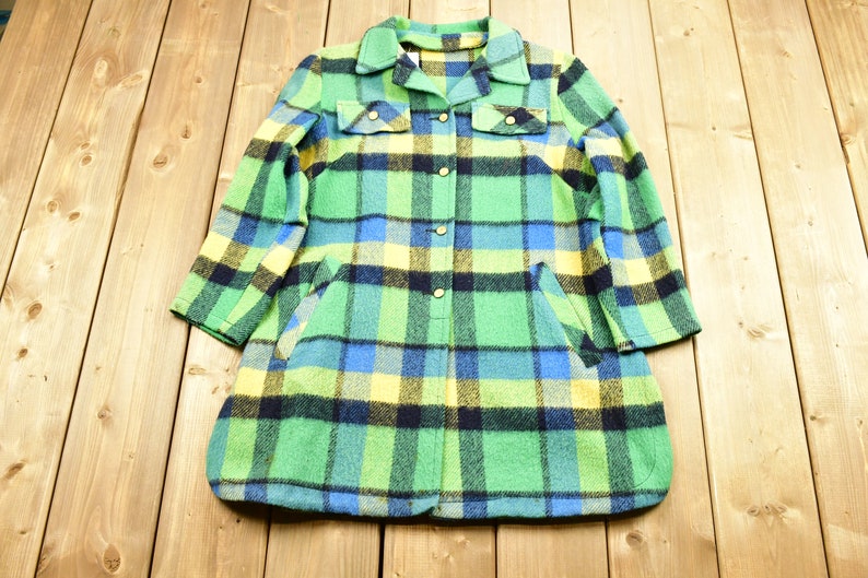 K&ouml;nnte beinhalten: Eine lang&auml;rmelige karierte Jacke mit Knopfleiste. Die Jacke ist gr&uuml;n, blau, gelb und schwarz.