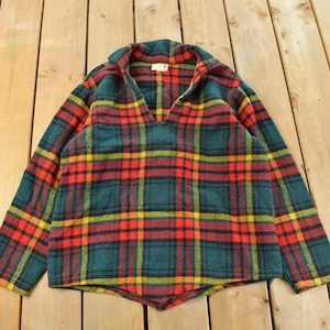 Op de afbeelding: Een vintage geruit shirt in een groen, rood en geel patroon. Het shirt met lange mouwen heeft een V-hals en een relaxte pasvorm. Het shirt is gemaakt van een zacht, warm materiaal, perfect voor koeler weer.