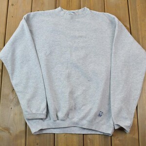 May include: A gray sweatshirt with a small logo on the bottom right side.