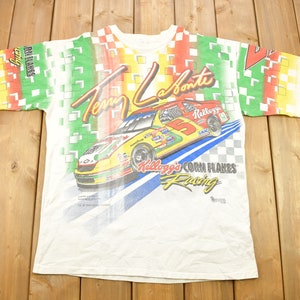 May include: White t-shirt with a colorful all-over print featuring a race car with the text "Terry Labonte" and "Kellogg's Corn Flakes Racing".