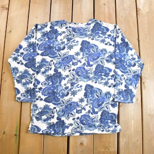 May include: A white long-sleeved shirt with a blue and gray floral pattern.