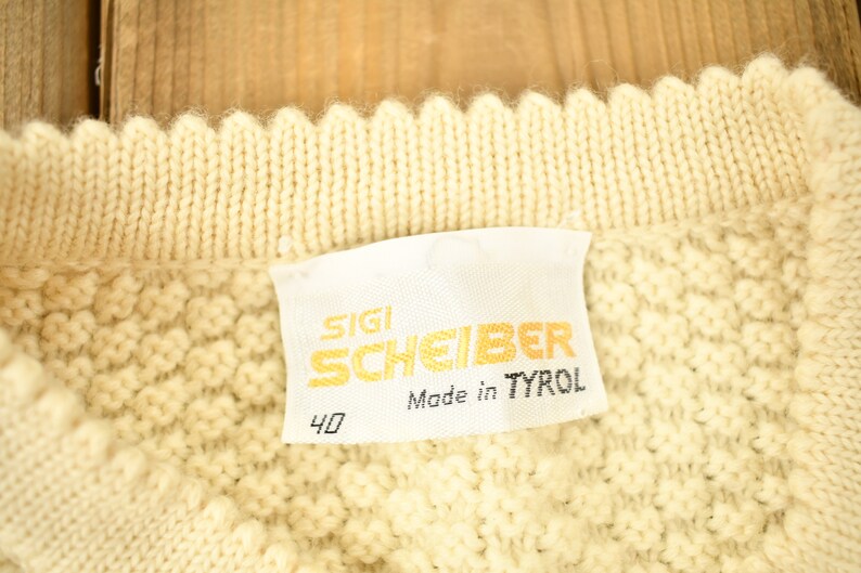 May include: A white knitted sweater with a label that reads "SIGI SCHEIBER Made in TYROL" and the number "40".