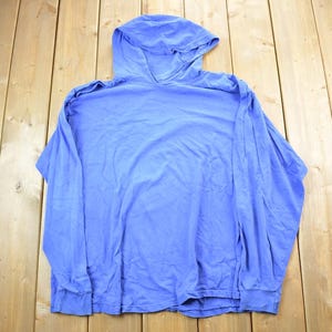 Könnte beinhalten: Ein hellblauer Kapuzenpullover mit langen Ärmeln und lockerer Passform.