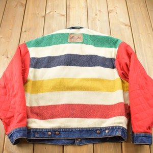 May include: A red and blue striped denim jacket with a multi-colored wool insert. The wool insert has stripes of green, navy blue, yellow, red, and white.