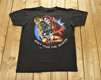 May include: Black t-shirt with a graphic print of a woman being held by a skeleton wearing a red robe. The text "Don't Fear The Reaper" is printed below the graphic.