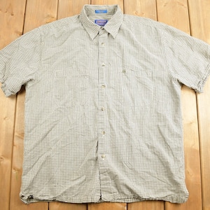 Op de afbeelding: Kort mouwen overhemd met een klein grijs en wit geruit patroon. Het overhemd heeft een kraag, een borstzak en een knoopsluiting. De stof is lichtgewicht en geschikt voor warm weer.