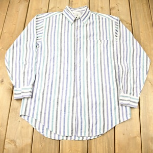 Op de afbeelding: Een wit overhemd met lange mouwen en knopen met blauwe, groene en grijze verticale strepen.