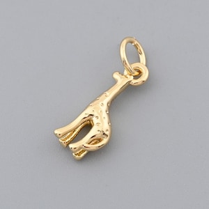 Può includere: Un ciondolo a forma di giraffa color oro con un piccolo anello nella parte superiore per attaccarlo a una collana o un braccialetto. Il ciondolo ha un design dettagliato, inclusi macchie e un lungo collo. La giraffa è in piedi su quattro zampe.