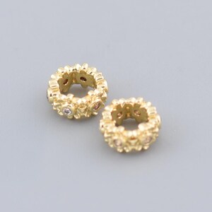 Può includere: Due anelli d'oro con piccole pietre preziose incastonate nel metallo. Gli anelli sono testurizzati e hanno un design delicato.