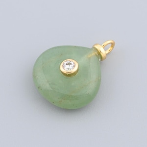 May include: A light green, teardrop-shaped pendant with a gold-coloured bail. The pendant has a small, round, clear gemstone set in the centre. The bail is also gold-coloured.