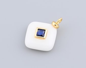 May include: A white square pendant with a gold-coloured bail. The pendant features a square, dark blue gemstone set in a gold-coloured frame. The pendant is a jewellery item.