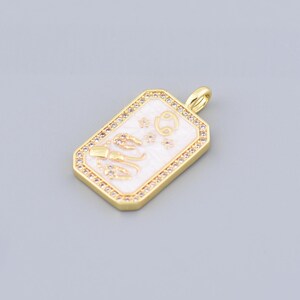 May include: Gold pendant with a white, rectangular, enamel-like surface featuring a zodiac symbol. The pendant is surrounded by a border of small, clear rhinestones.