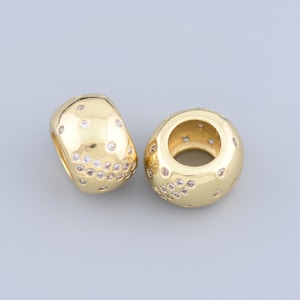 Peut inclure: Deux espaceurs de perles dorés avec un motif circulaire et de petits strass transparents.