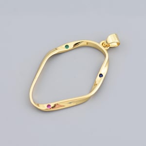 May include: A gold pendant with a unique, twisted shape. It has three small gemstones: green, blue, and red. The pendant is designed with a loop at the top for a chain. The pendant is made of gold.