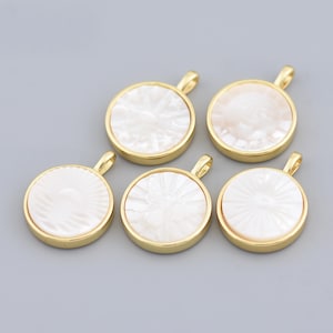 May include: Six round pendants with a gold-colored border and a white, textured center. Each pendant has a small loop at the top for attaching to a chain or other jewelry component. The pendants are arranged on a light gray background.